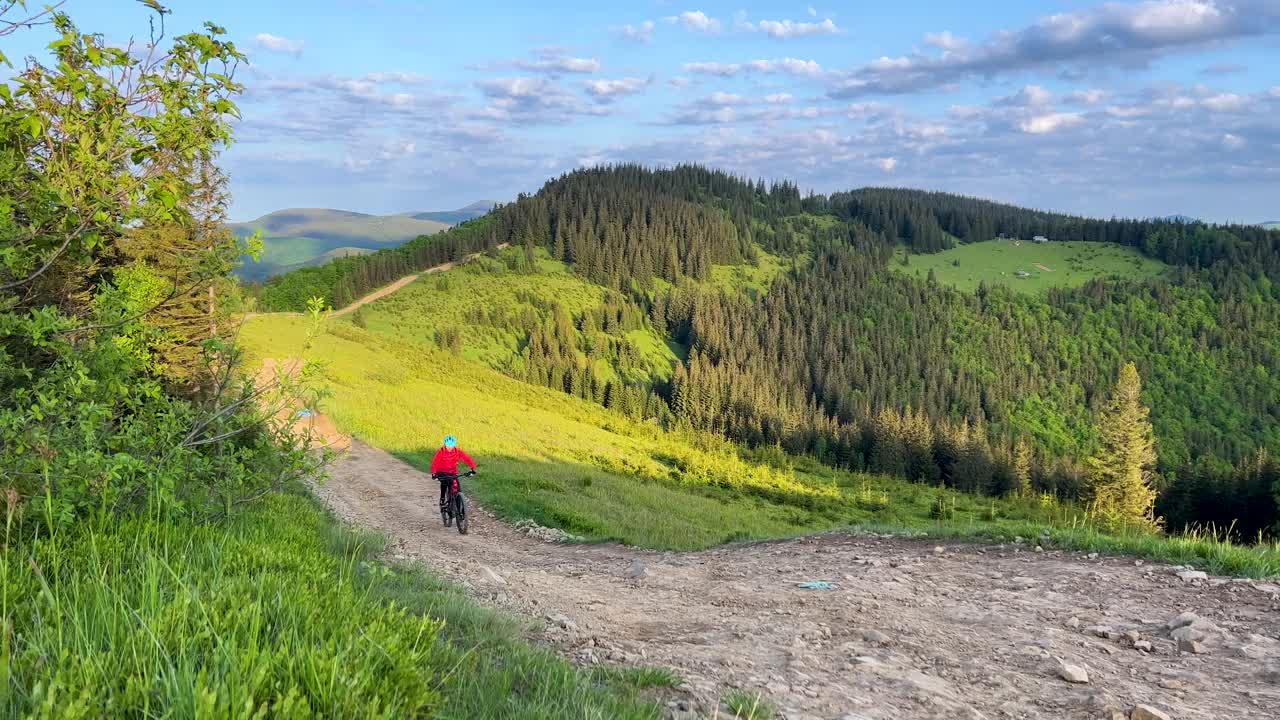 骑电动山地车的人沿着山上长满草的小路在户外骑行。视频素材