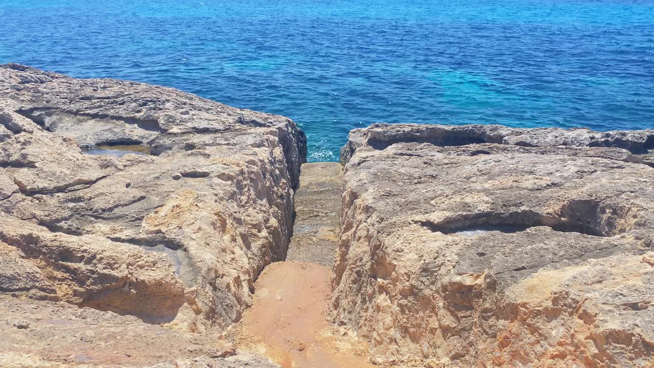 在通往大海的岩石上切割，背景是科米诺岛和马耳他视频素材