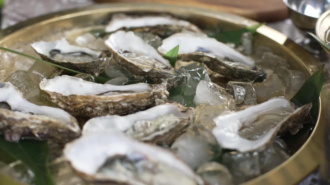 用冰块打开生蚝。金属托盘上的新鲜海鲜。餐厅菜单，节食食谱视频素材