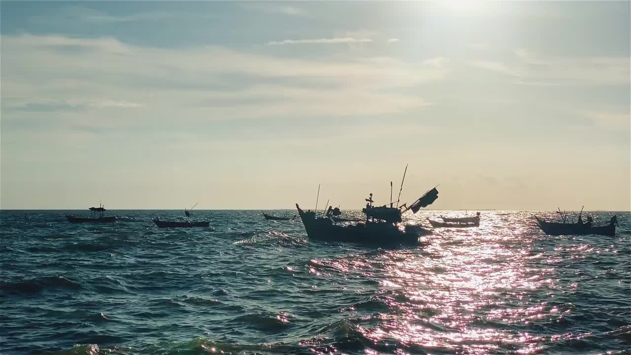 日落时的渔船在海滩风景，日出或日落时的渔船，太阳在云上闪烁，天空和云有力量激发敬畏或惊奇的感觉视频下载