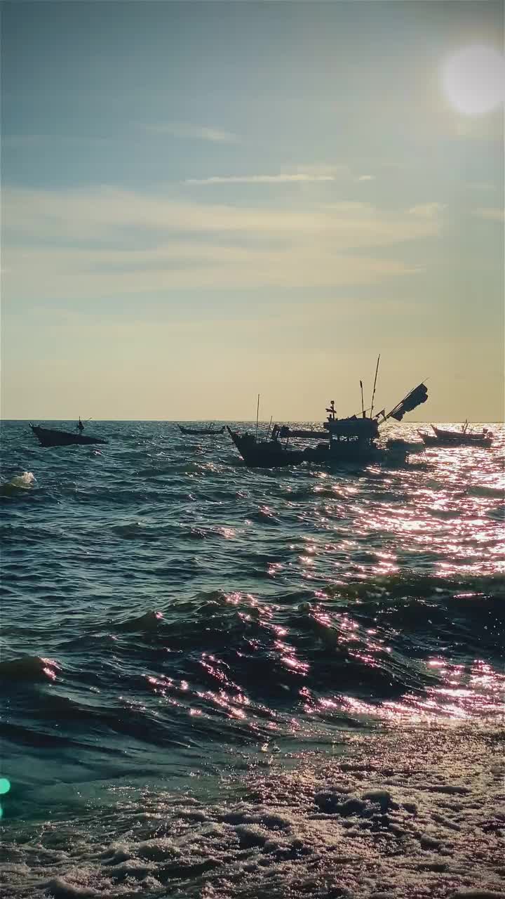 日落时的渔船在海滩风景，日出或日落时的渔船，太阳在云上闪烁，天空和云有力量激发敬畏或惊奇的感觉视频下载