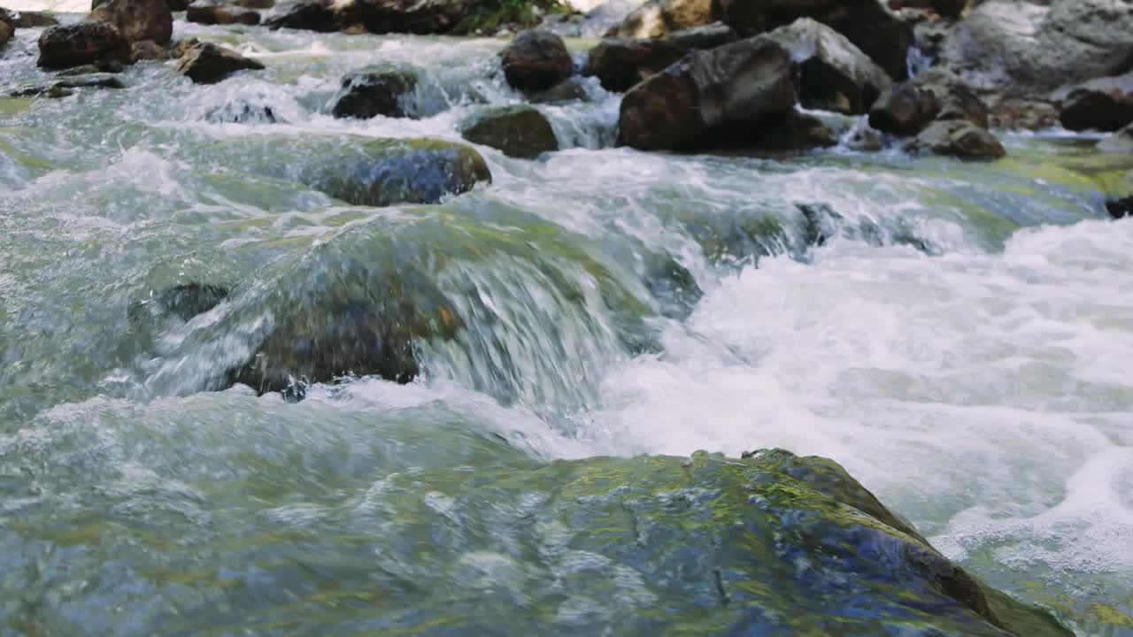 一个迷人的特写镜头，一个原始的山溪冲过光滑的岩石。清澈的海水反射着阳光流过自然景观视频素材