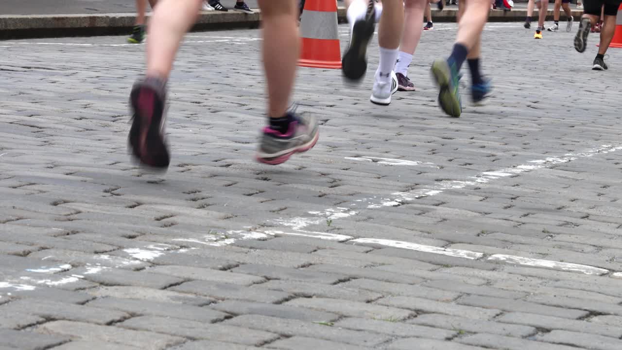 人们在鹅卵石街道上奔跑，双腿紧挨着铺路石视频下载