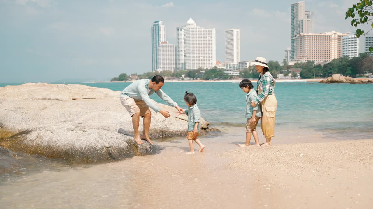 周末在海滩上散步的亚洲家庭。视频下载