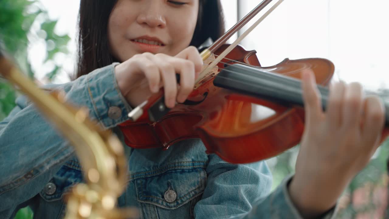 年轻的亚洲女子正在练习拉小提琴视频素材