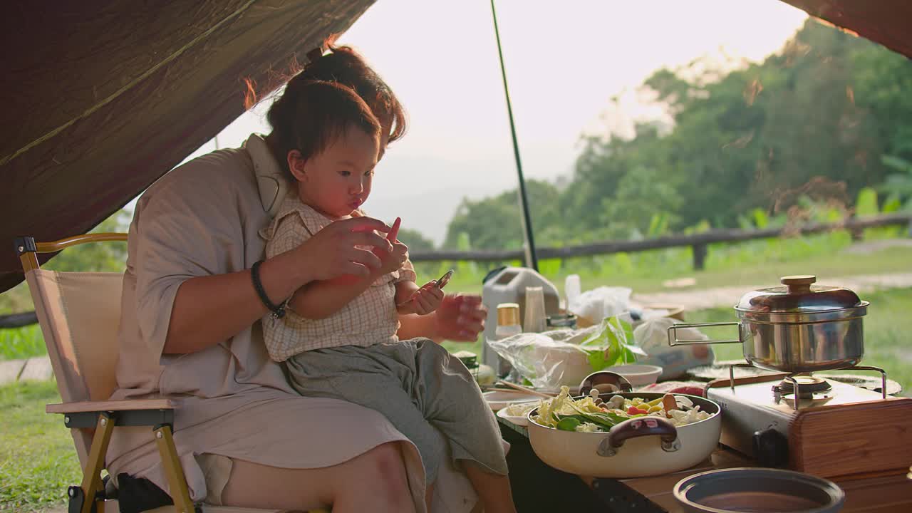 母亲和孩子在风景优美的自然环境中享受户外露营餐，有新鲜的蔬菜和烹饪设备视频素材