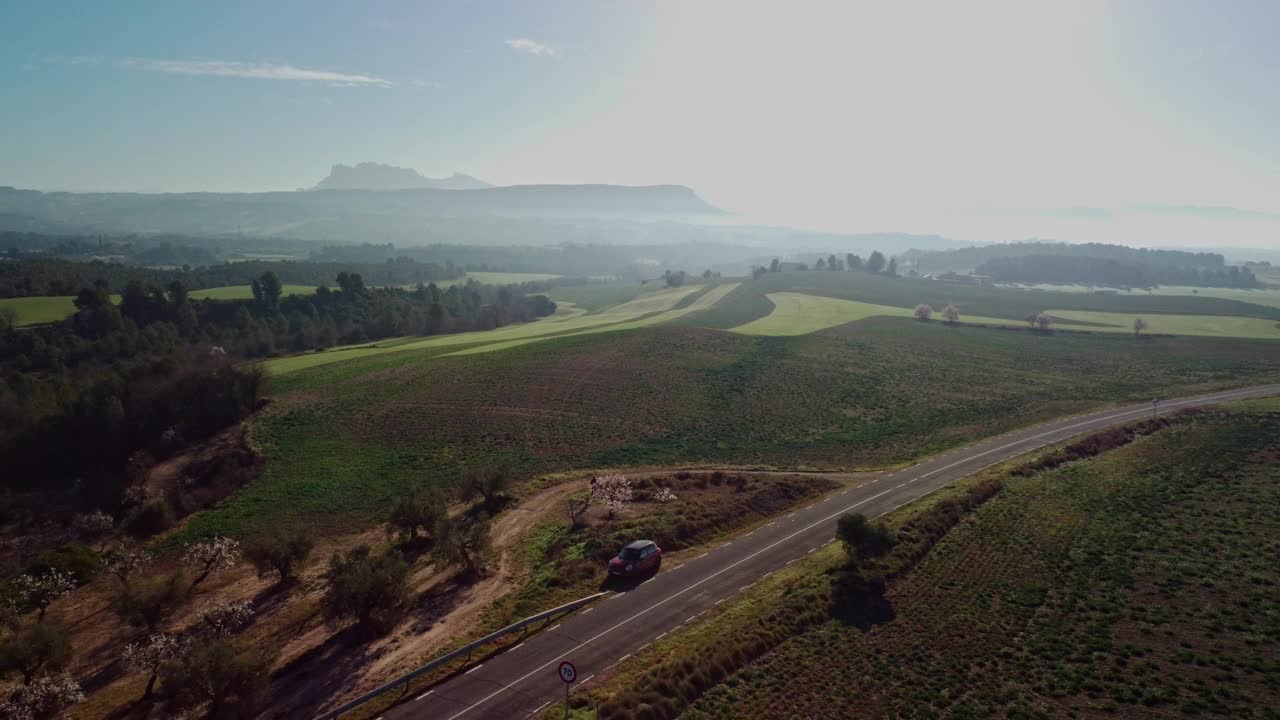 晴朗的天空下，一辆汽车沿着风景优美的乡村道路行驶视频素材