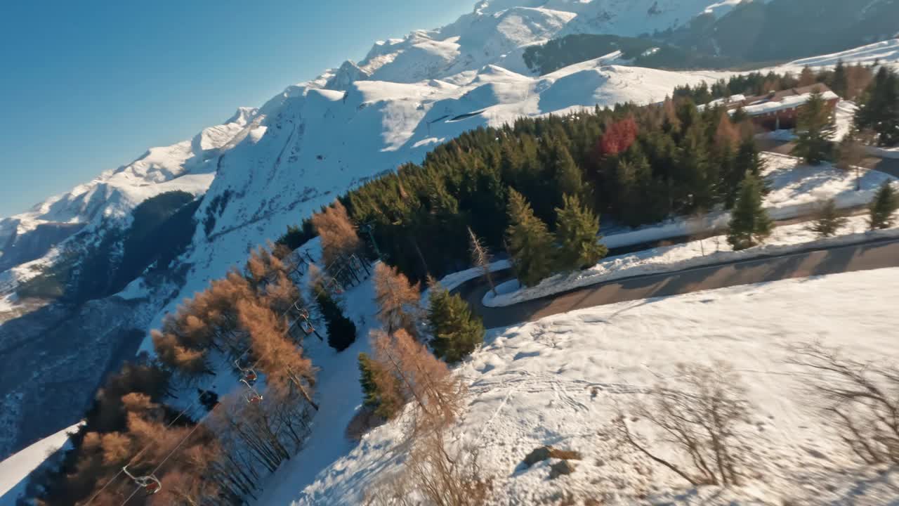 FPV无人机飞过白雪皑皑的森林，背景是雄伟的山脉视频素材