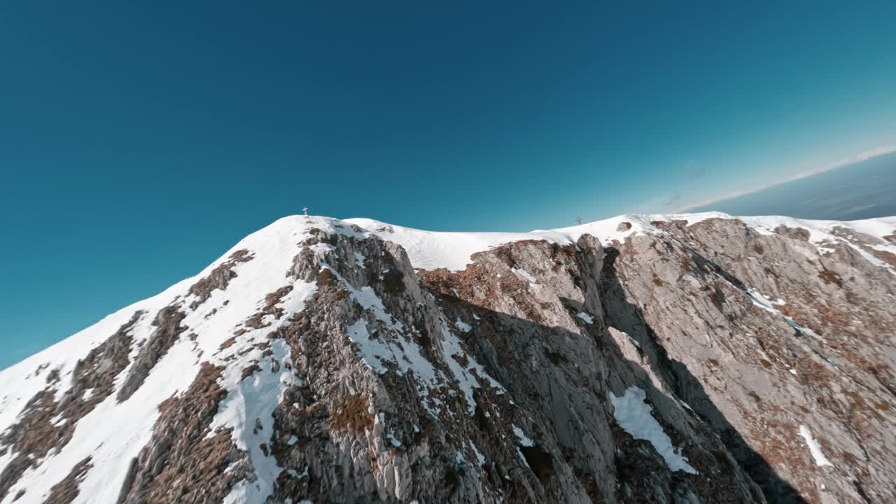 在一个晴朗的日子里，FPV无人机在白雪皑皑的山脊上翱翔视频素材