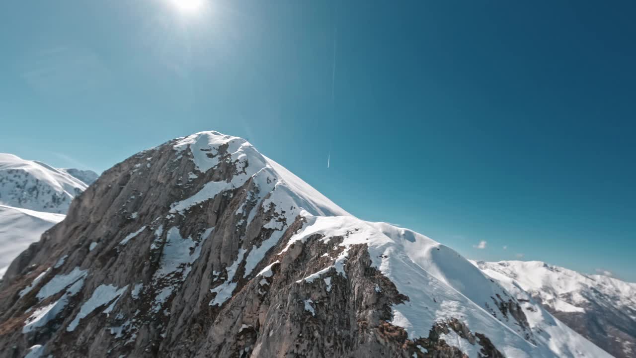 被白雪覆盖的山峰，明亮的阳光和清澈的蓝天下，无人机拍摄视频素材