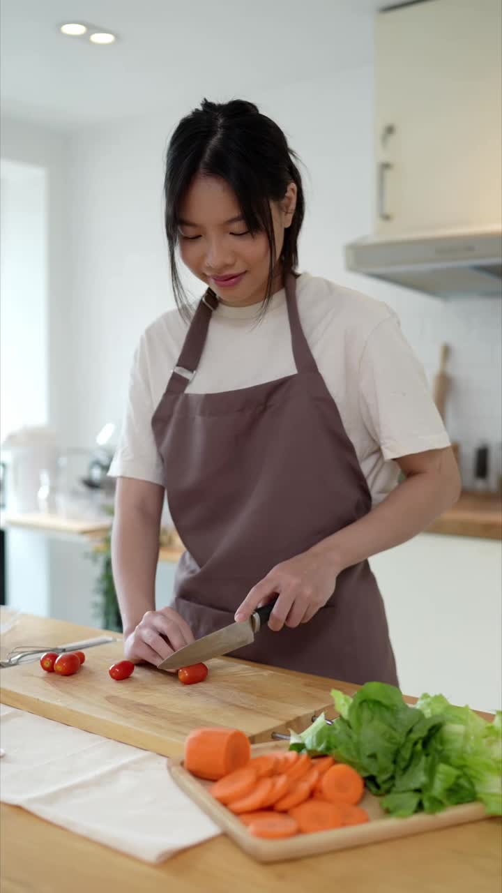 这位亚洲妇女正在厨房切西红柿，准备在家里做亚洲菜视频素材