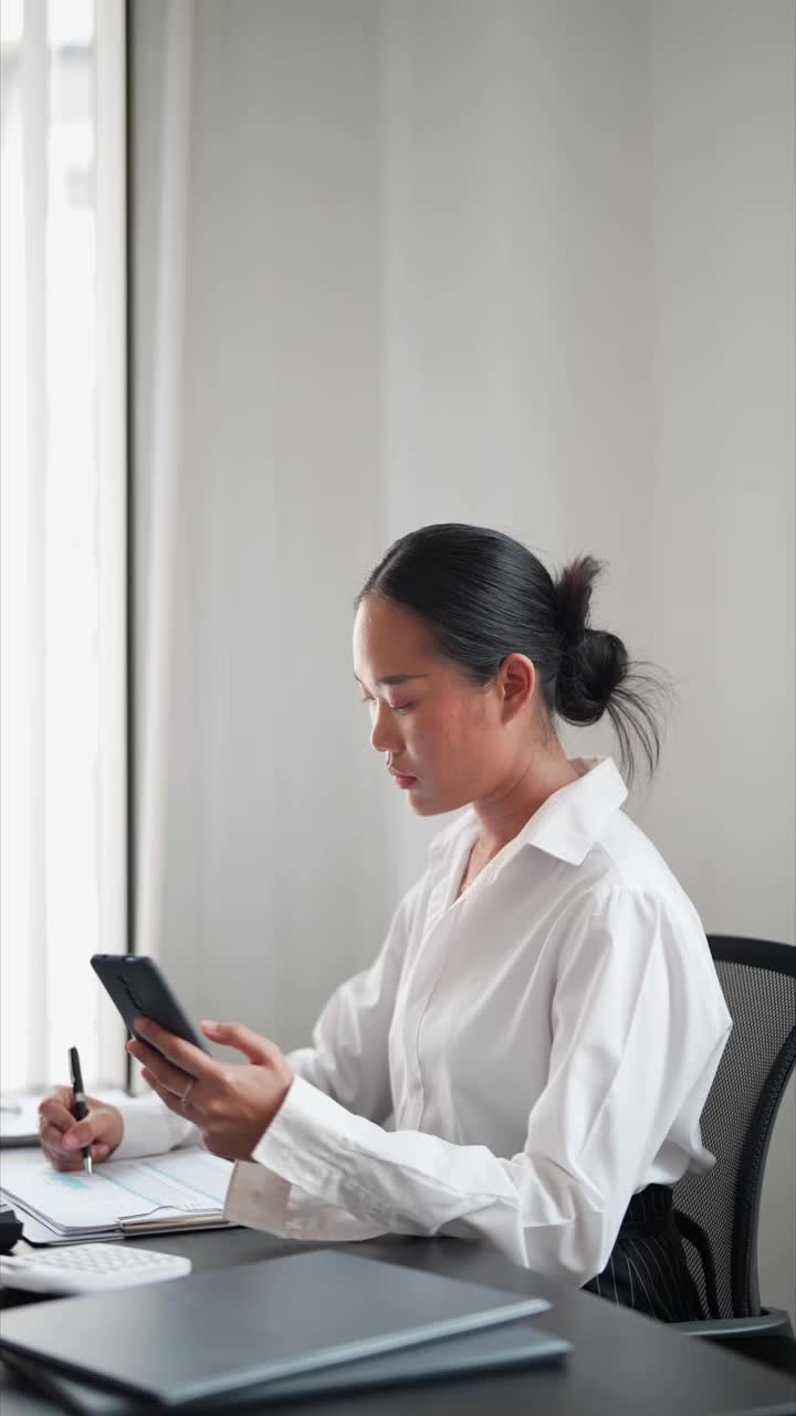 一名亚洲女商人在办公室愉快地使用智能签到系统，享受着这项福利。高效的工作和快乐的工作时刻视频素材