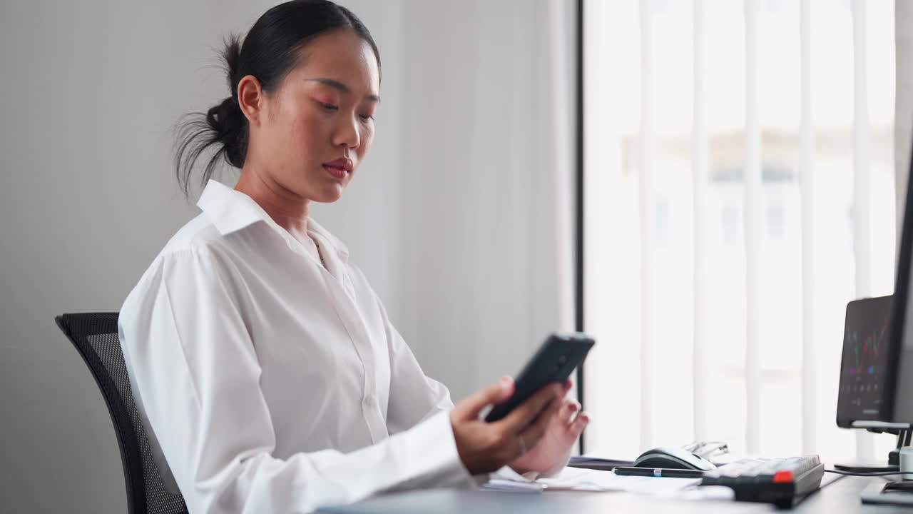 一位亚洲女商人用智能手机随时了解办公室的最新消息。及时了解最新情况，以便做出明智的决策视频素材