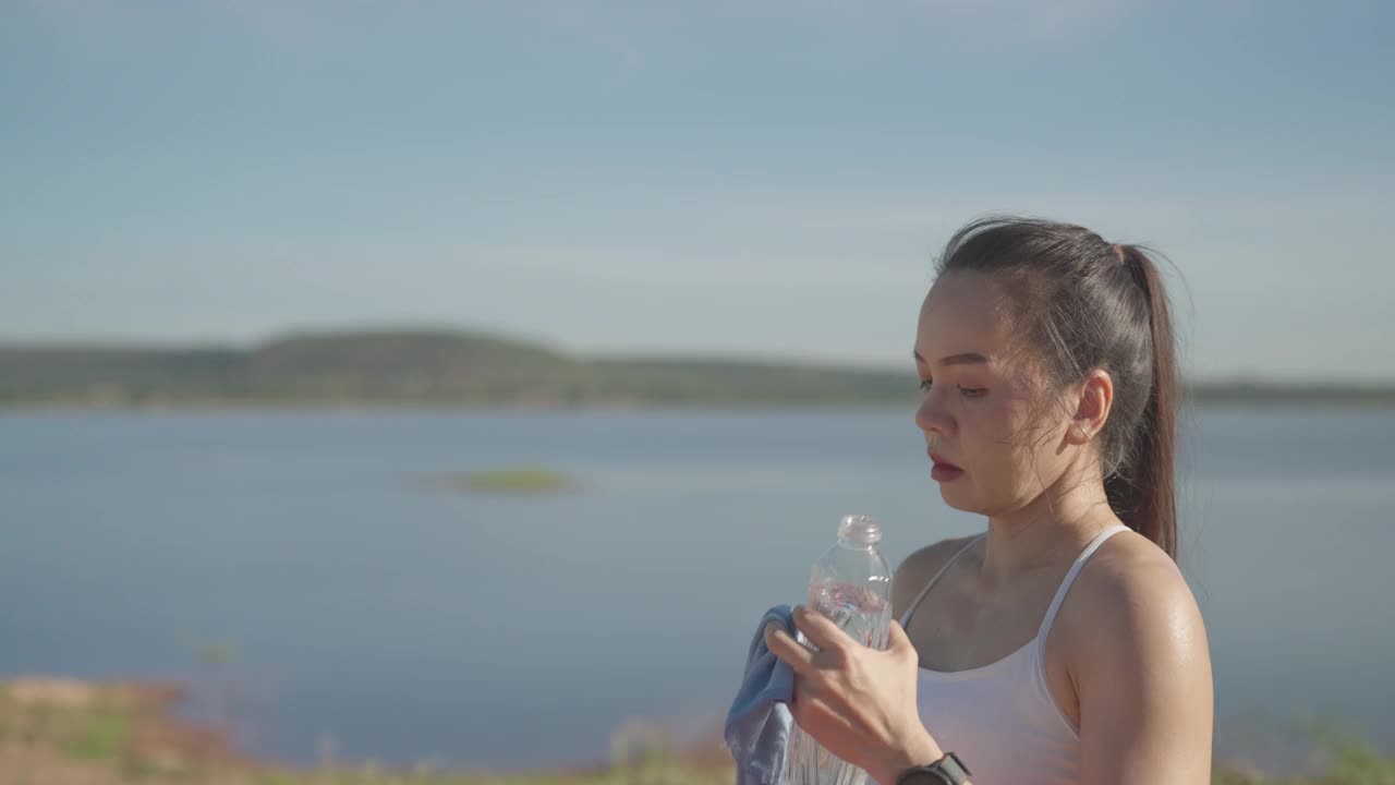 一个女人站在湖边喝水视频素材