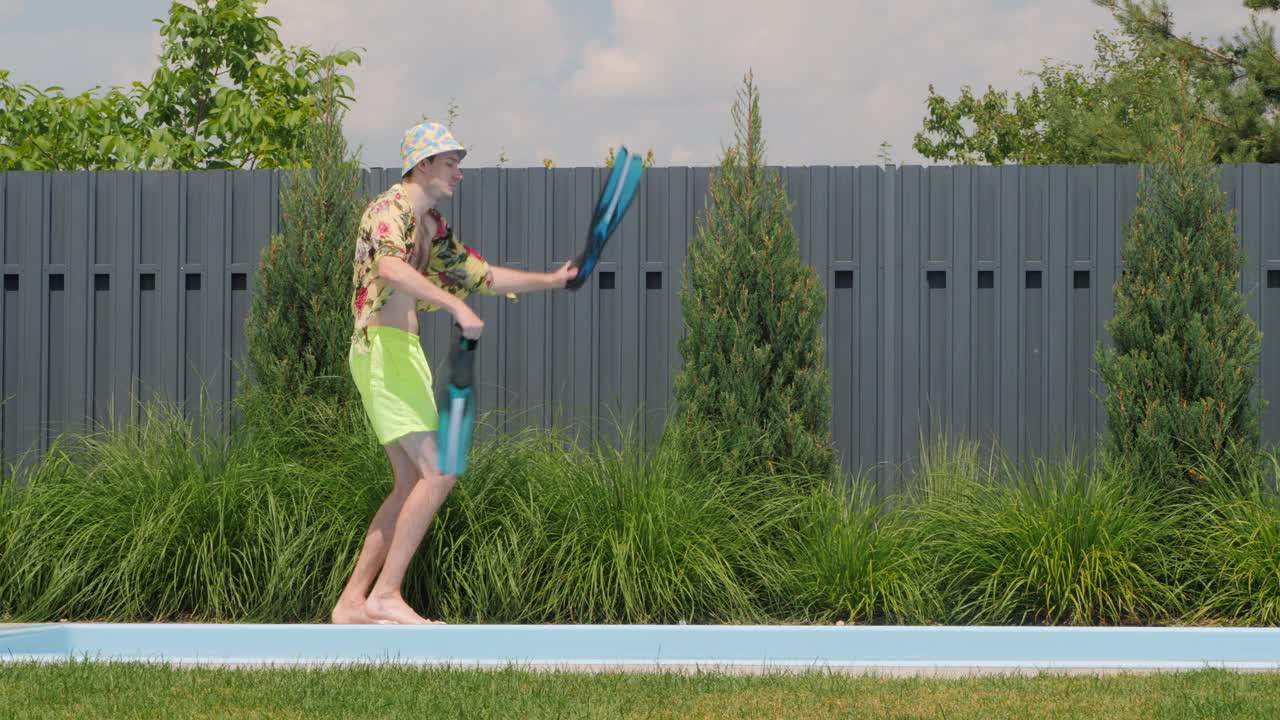 一名男子拿着脚蹼在泳池边欢快地跳舞。视频下载