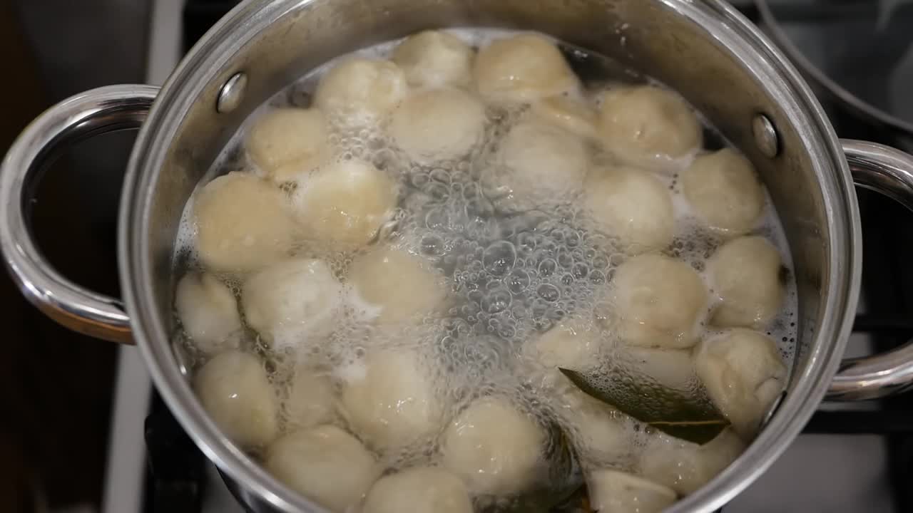 饺子是在平底锅里煮的。在锅里煮饺子。在厨房做饭视频素材