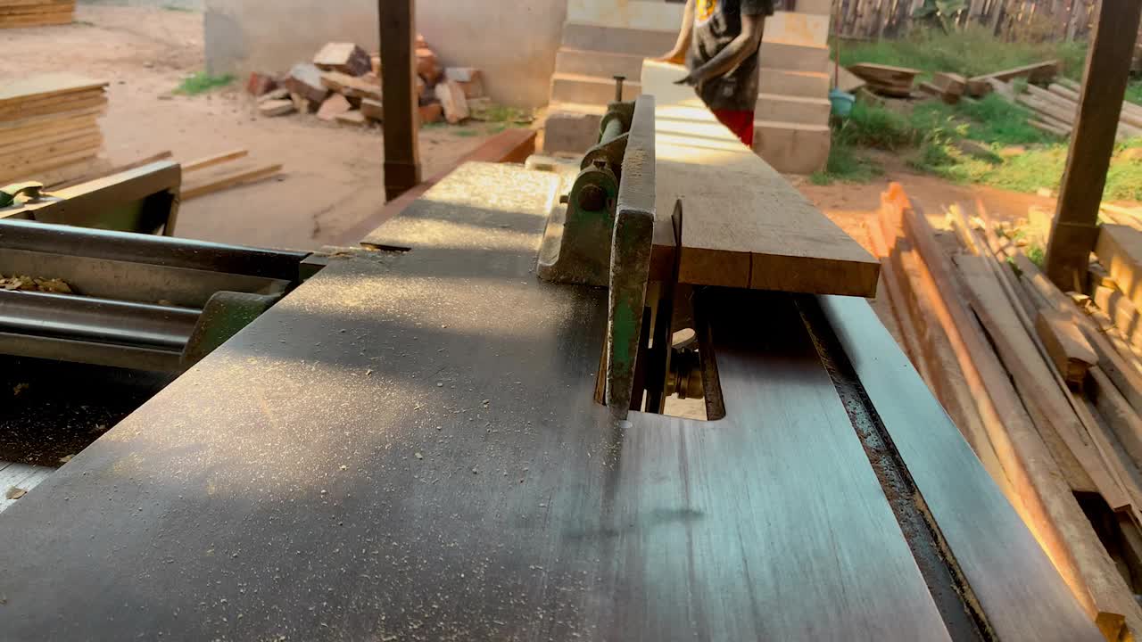 身份不明的非洲专业木匠，在车间里用台式圆锯把一块木板切成小块视频素材