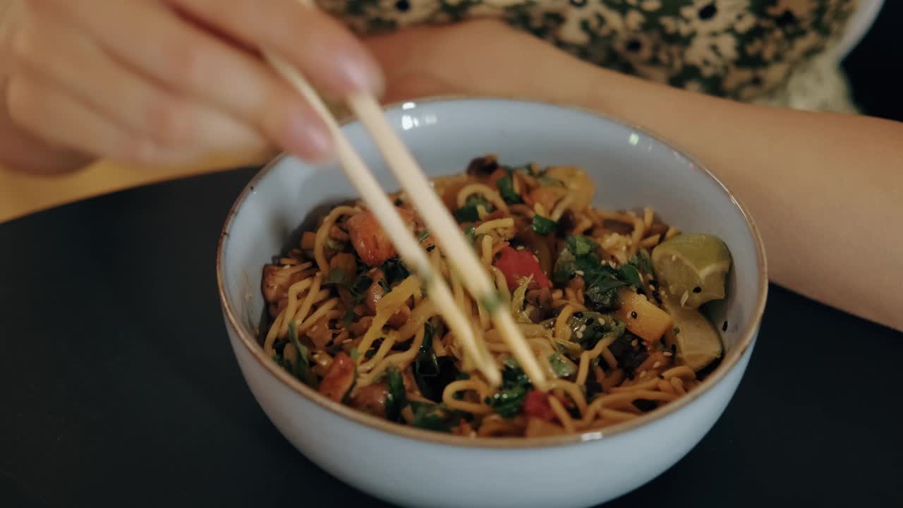 一个人用筷子享用一碗亚洲炒面的特写。理想的食品和烹饪内容。视频素材