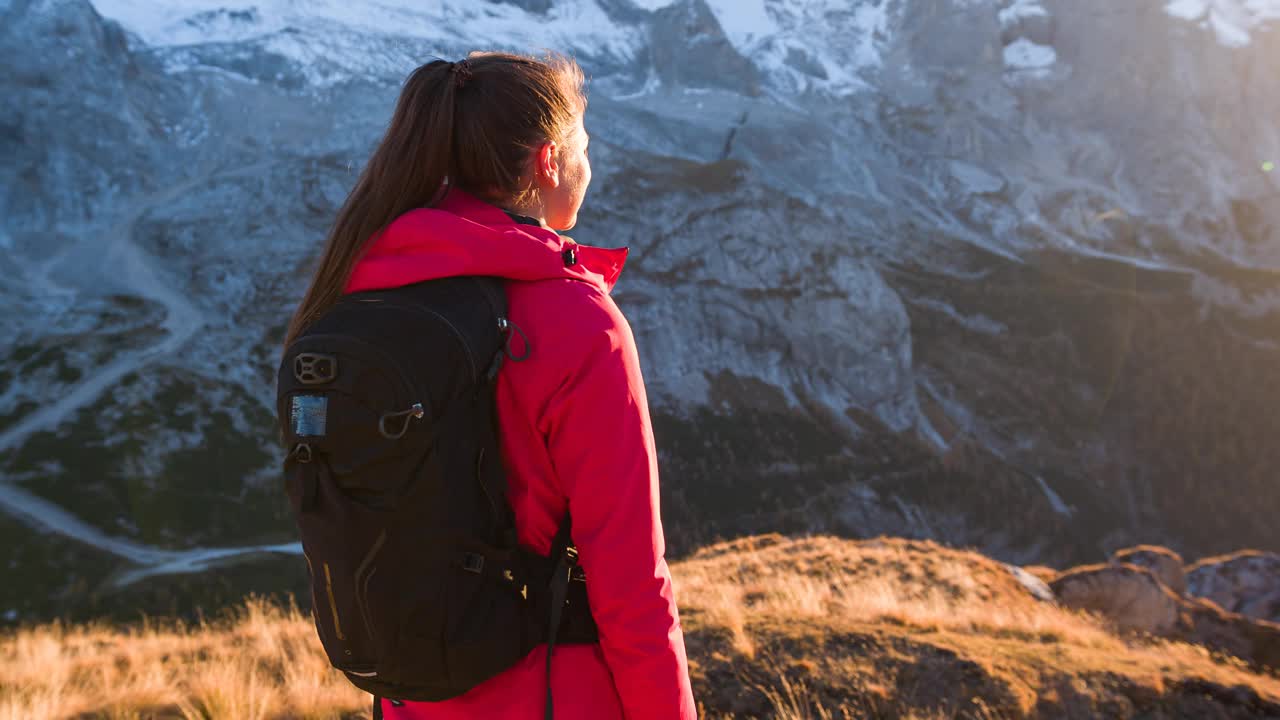 女徒步旅行者看着山谷和周围群山的壮丽景色视频下载