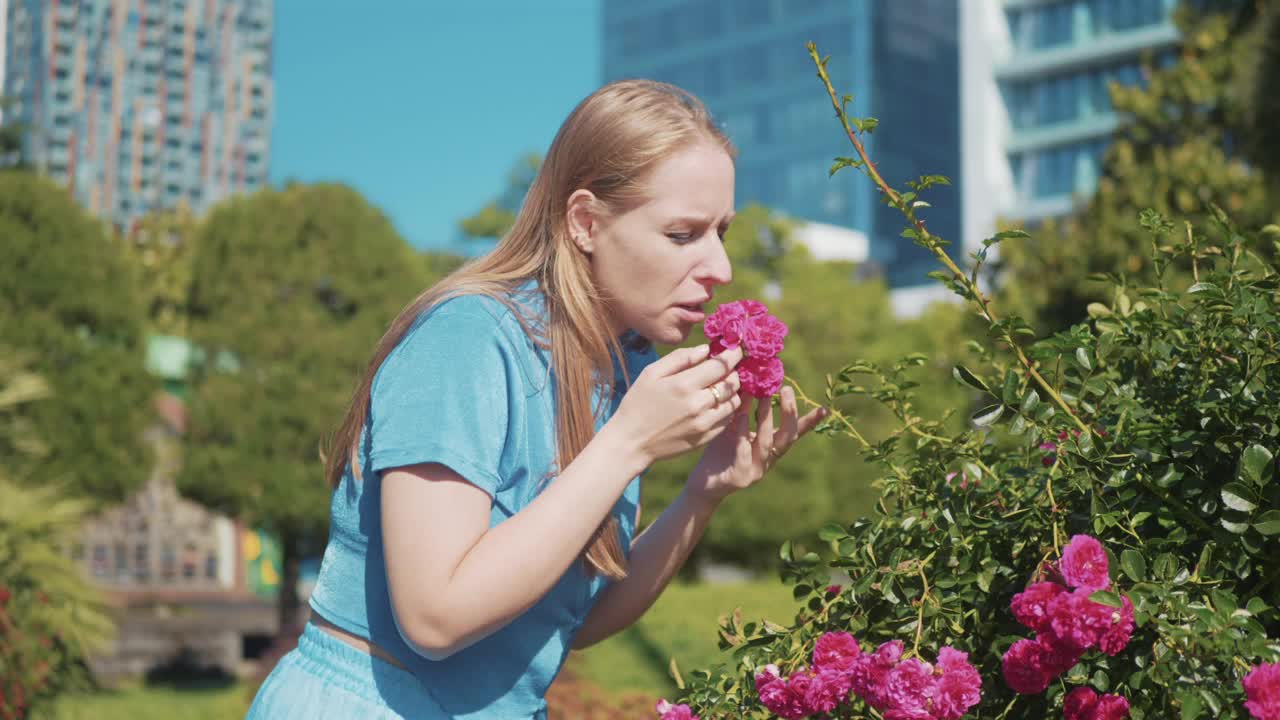 年轻女子在城市公园闻花打喷嚏，季节性过敏的概念。女性在夏季城市户外对花粉过敏视频素材