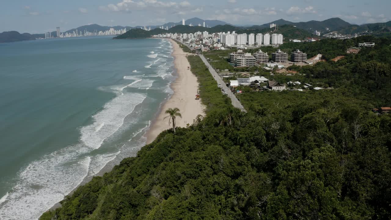 在Balneario Camboriu，大海，海滩和道路，背景是建筑和绿色的山脉视频素材