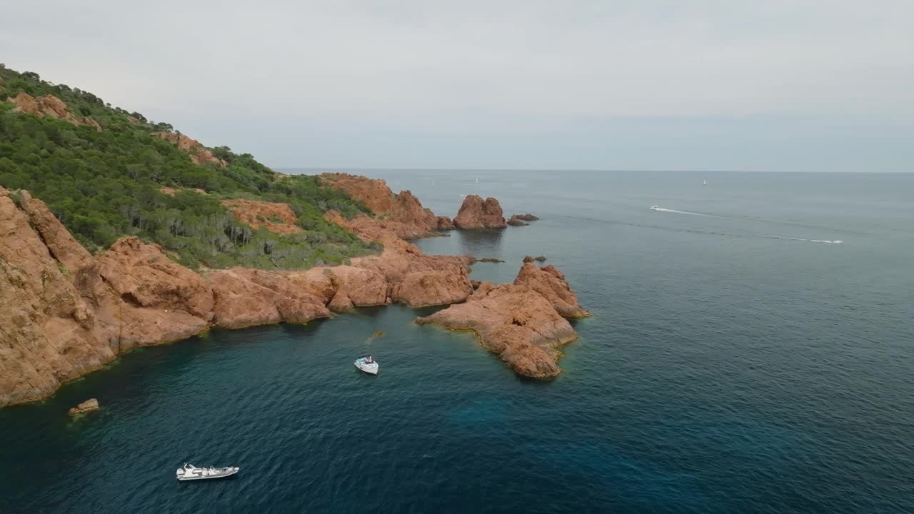 在法国圣拉斐尔的勒德拉蒙岛，蓝海上的岩石山和游艇视频素材