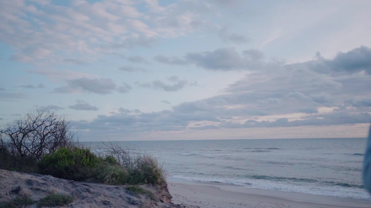 宁静的海滩景色，柔和的海浪，沙滩，宁静的天空与散落的云。视频素材