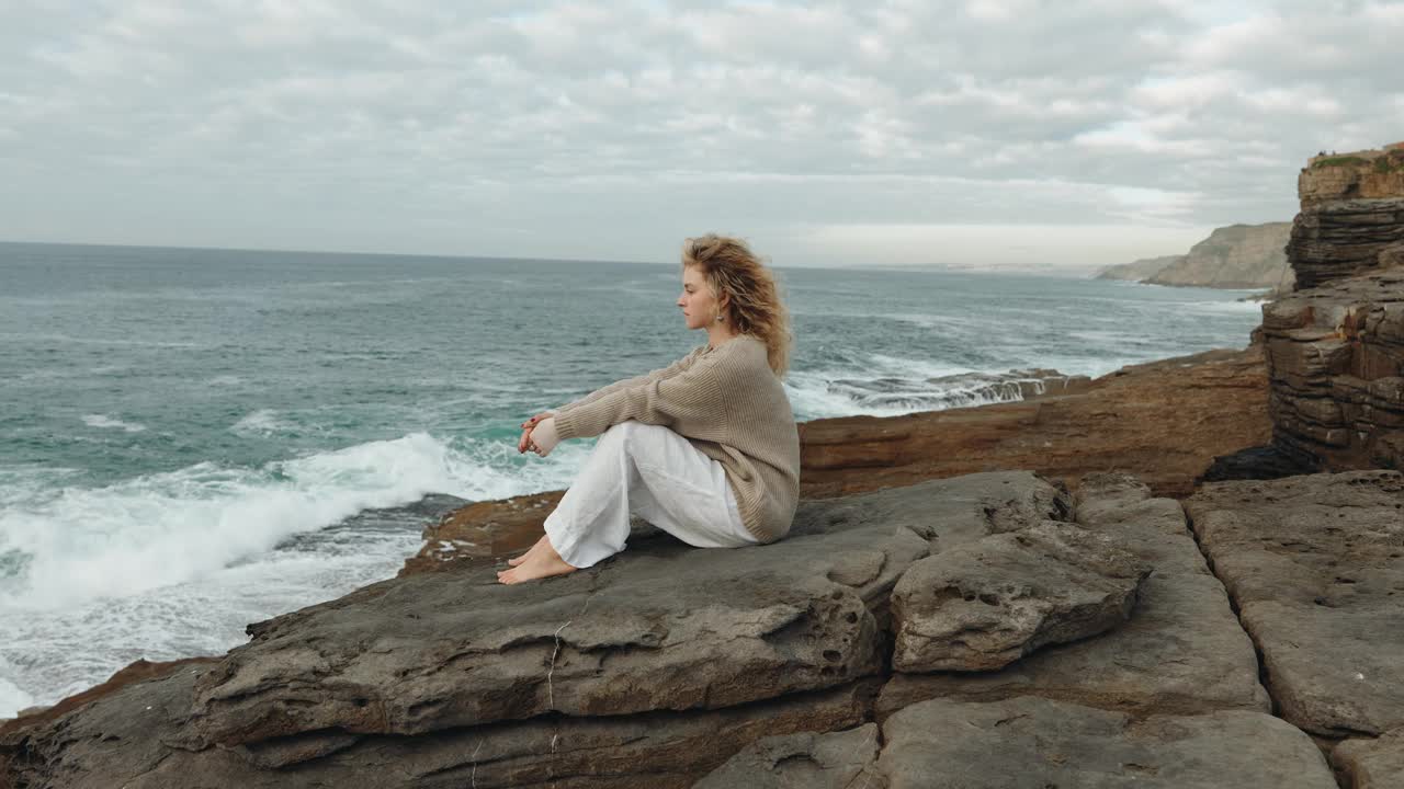 海边的沉思:一个女人在悬崖上沉思视频素材