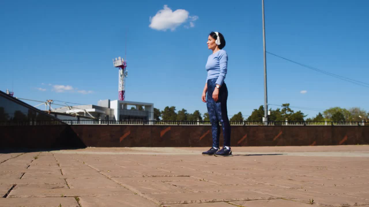 女人在腿部和臀部锻炼。在城市天空景观的屋顶上健身。视频素材