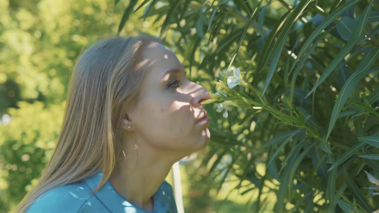 闻着开花植物的气味，对着纸巾打喷嚏，说明花粉过敏。一名女子在公园户外出现过敏反应视频素材