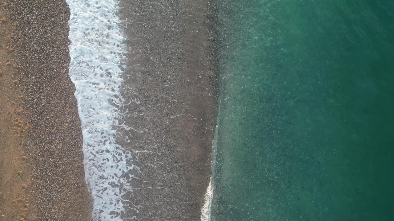 令人惊叹的中央鸟瞰图海浪和沙滩上的一个空的海滩在日出，4k背景视频下载