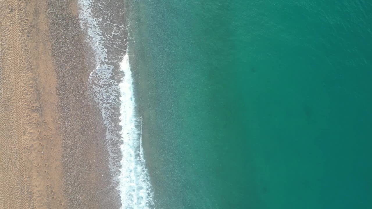 令人惊叹的中央鸟瞰图海浪和沙滩上的一个空的海滩在日出，4k背景视频下载