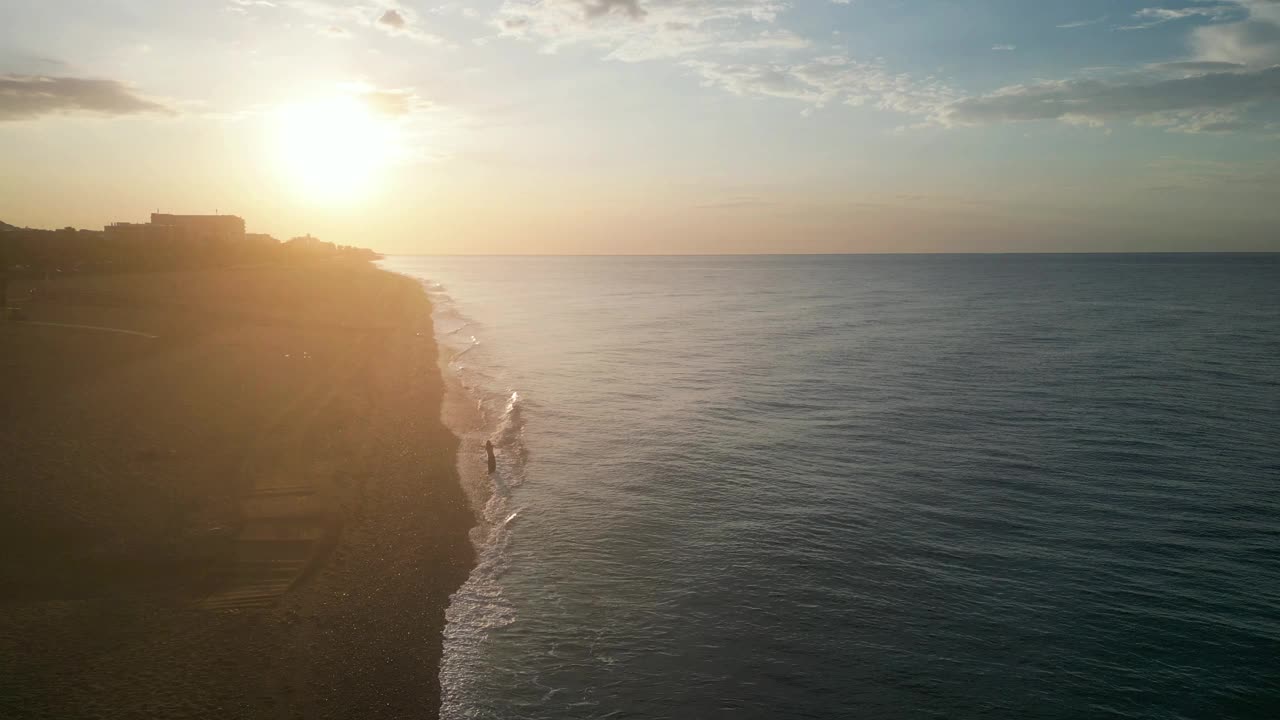 美丽的空中海景和女人在日出时空旷的海滩上，4K视频素材