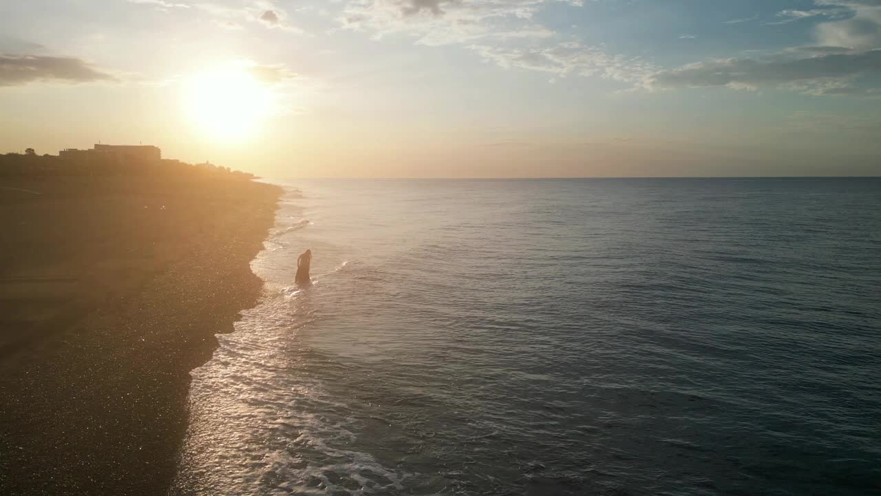 美丽的空中海景和女人在日出时空旷的海滩上，4K视频素材