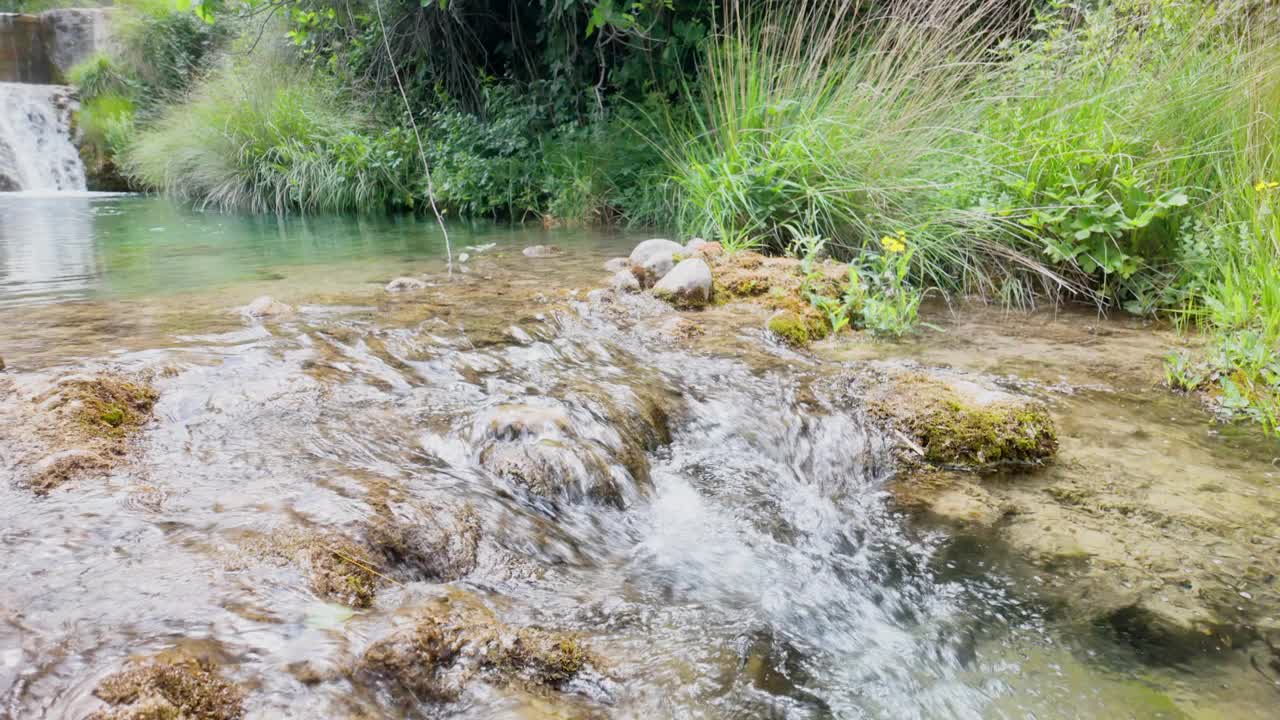 一股水流过岩石，穿过一片草地视频素材