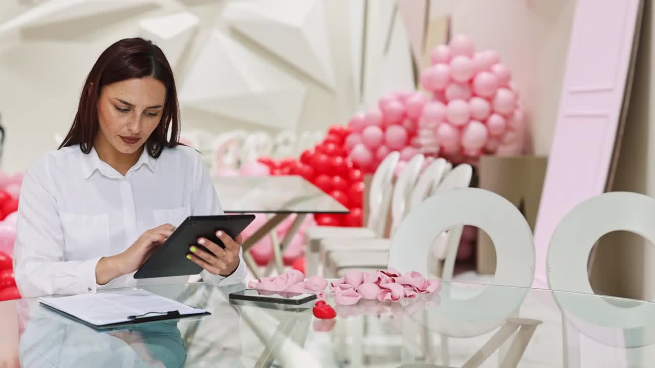 一位漂亮的女装饰师正坐在餐厅的桌子旁，手里拿着一台数码平板电脑视频素材