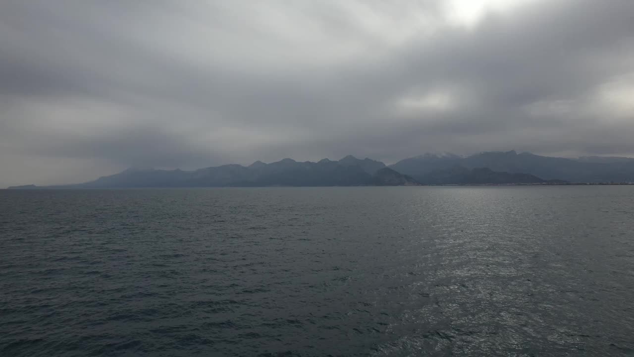 阴天波涛汹涌的海面上群山的景色。视频下载