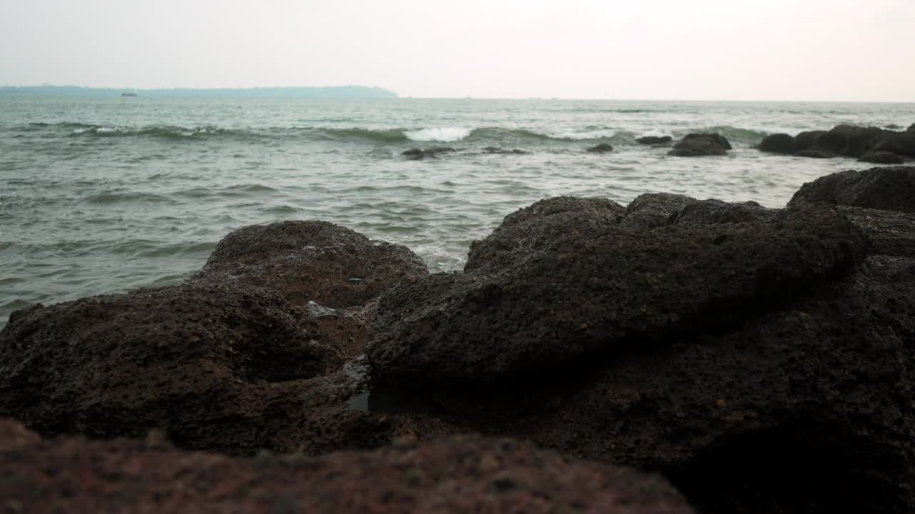 在一个多雾的海边天，海浪冲击着黑色的岩石视频素材