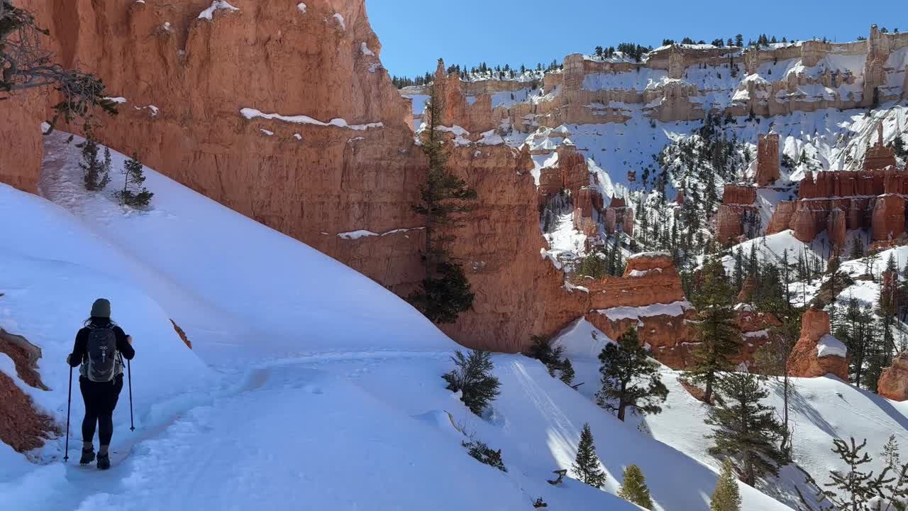 在白雪皑皑的冬天，在布莱斯峡谷国家公园圆形剧场徒步旅行的妇女视频素材