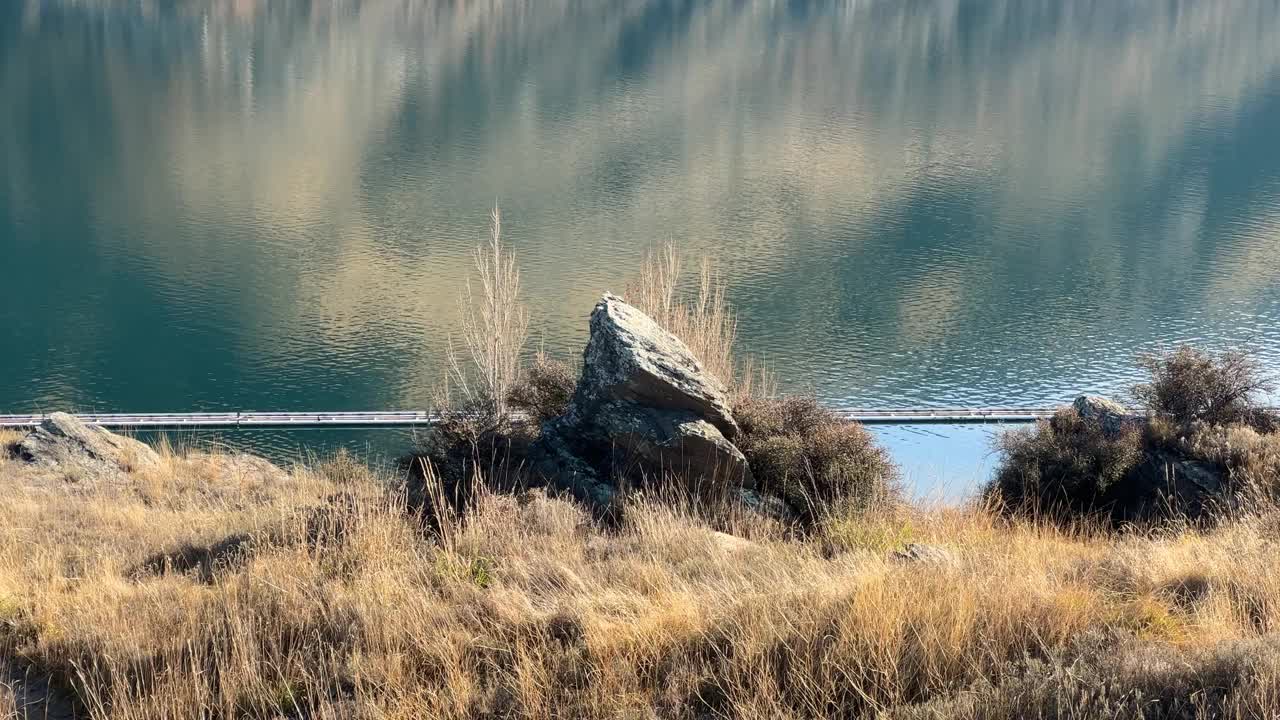 冰川湖岸边的干草和岩石，湖水平静视频下载