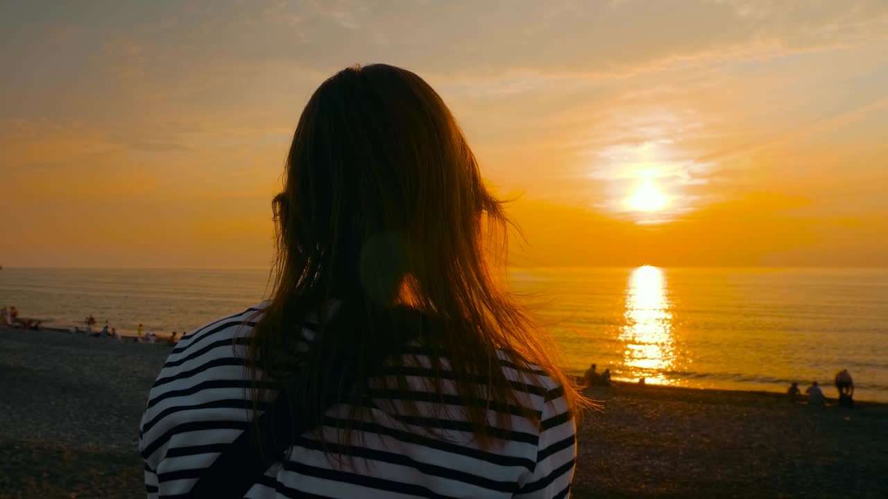 女人在海边看日落——慢镜头视频素材