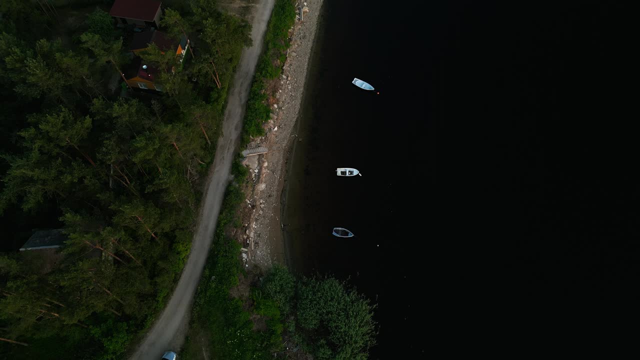 航拍画面显示，船只在宁静的湖边道路上行驶，周围环绕着郁郁葱葱的绿色植物，营造出一种宁静的景象视频素材