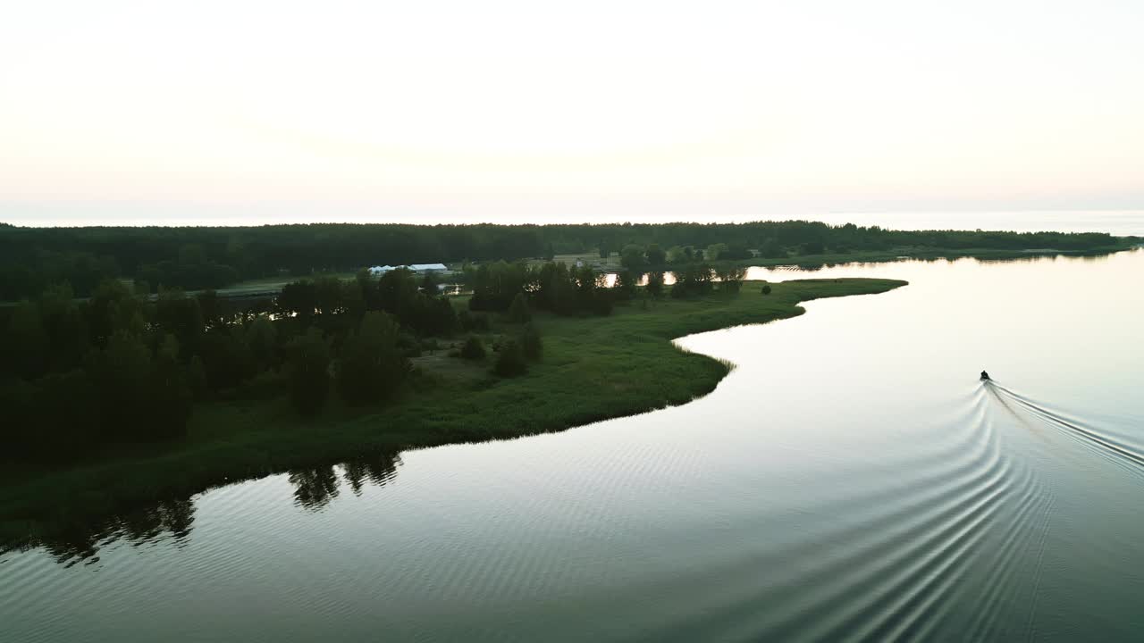 日出时一条宁静的河流与一艘平静漂流的船的宁静景色，从空中拍摄视频素材