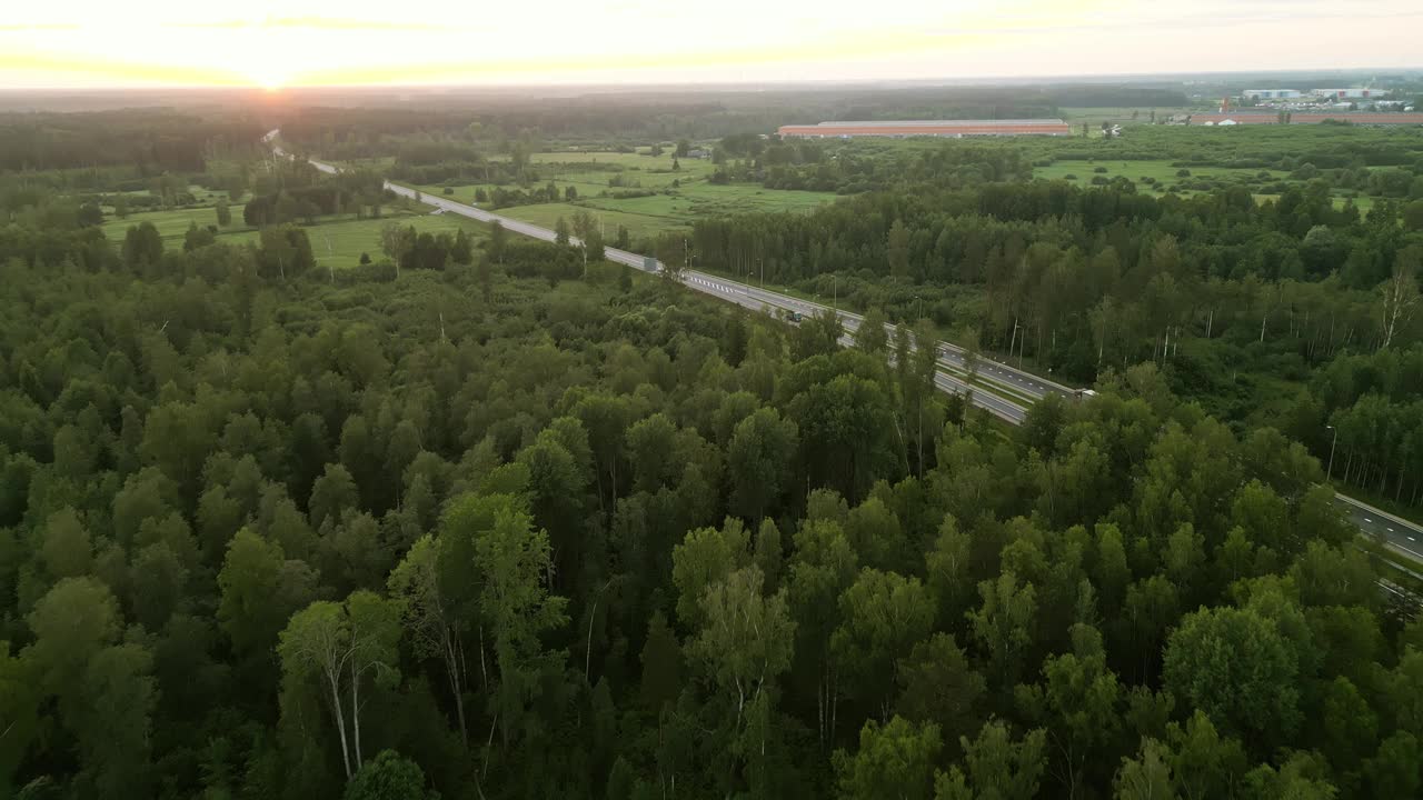 鸟瞰风景优美的高速公路蜿蜒穿过茂密的森林在日落，创造一个宁静的自然景观视频素材