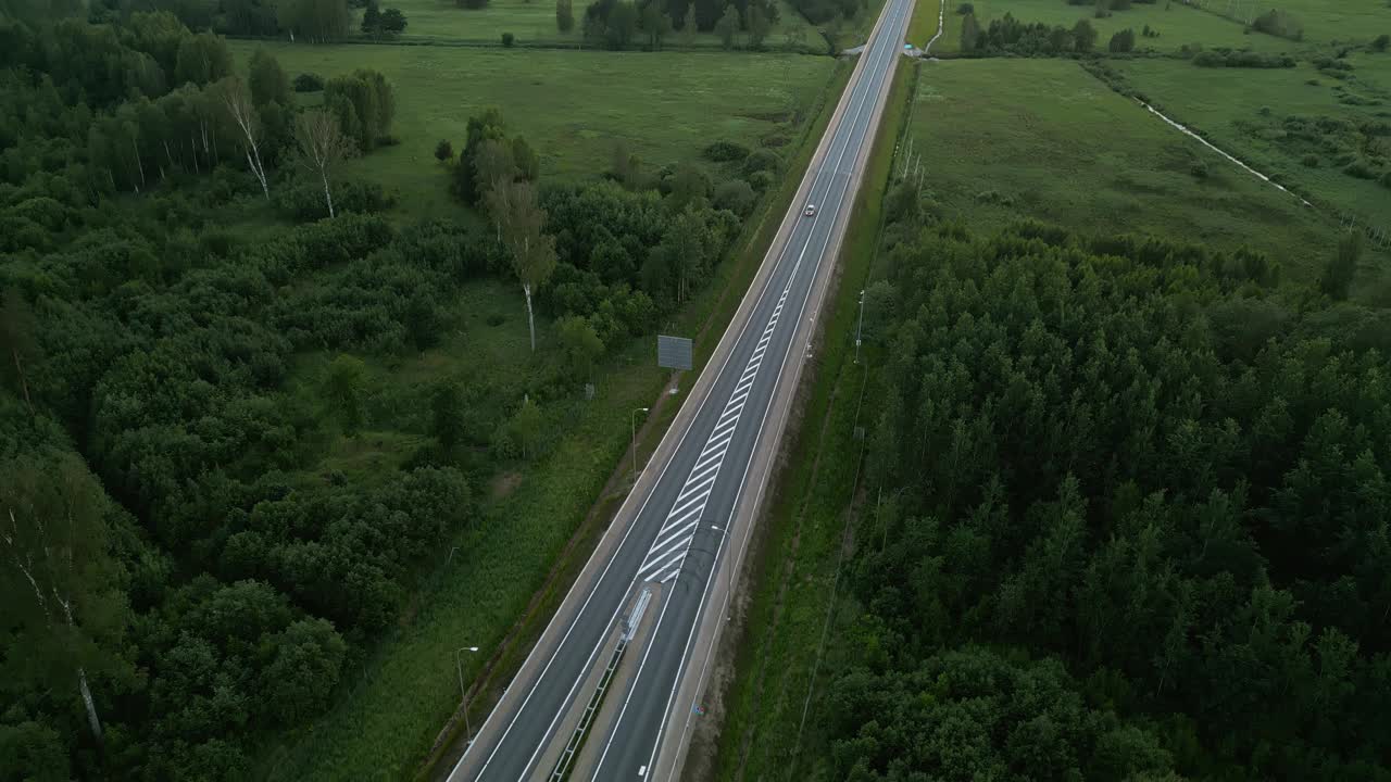 从空中俯瞰一条宁静的高速公路，郁郁葱葱的绿色景观为您提供了宁静而优美的景色视频素材