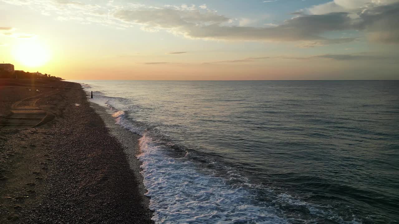 美丽的空中海景和女人在日出时空旷的海滩上，4K视频素材