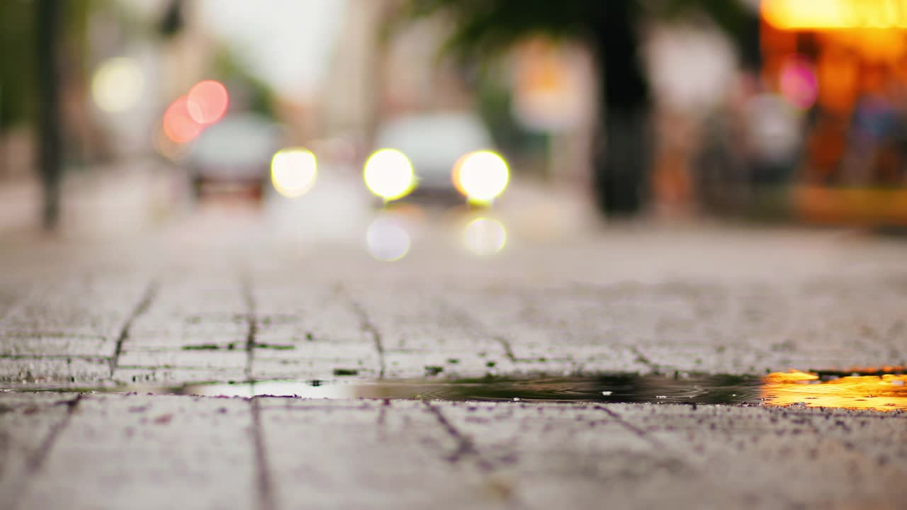 捕捉城市街道在雨夜的氛围，被发光的汽车灯和水坑的倒影照亮视频素材