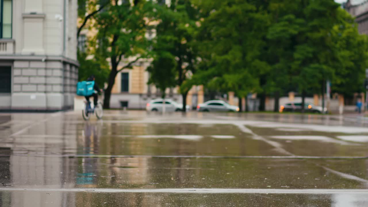 慢慢看一个下雨的城市街景，有建筑、树木、水坑、倒影和城市环境视频素材