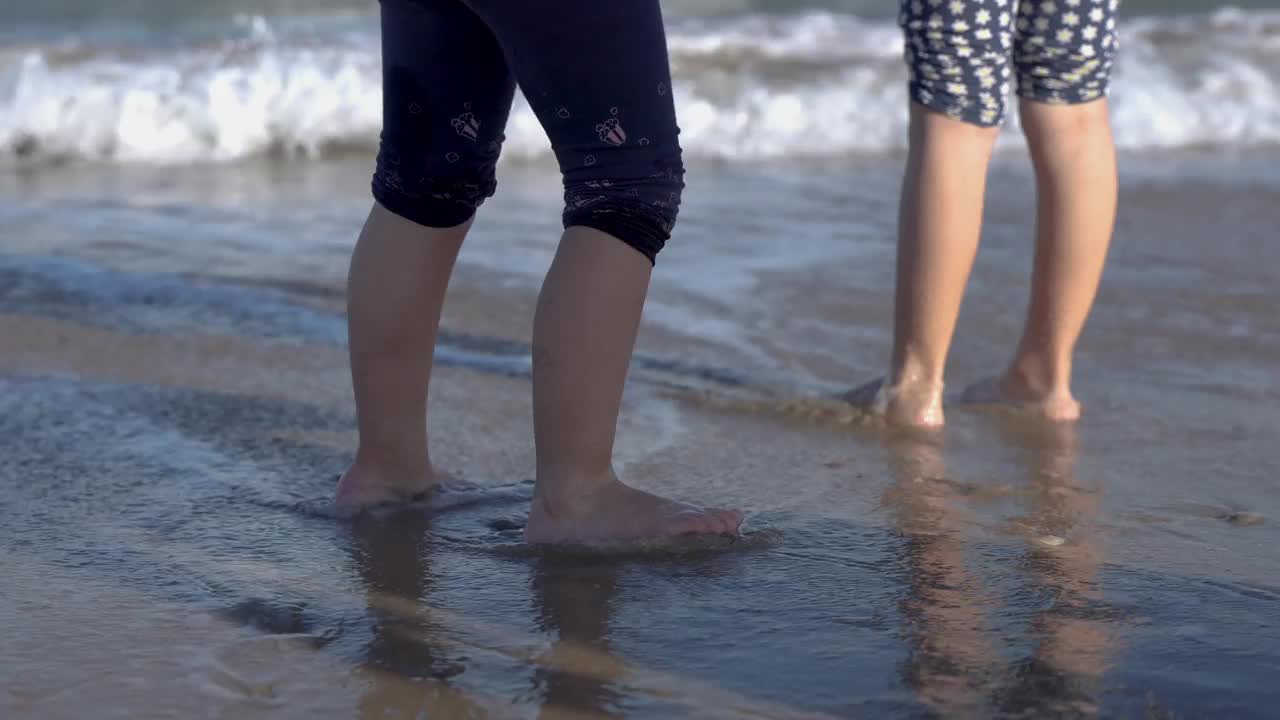 小女孩们在海边把脚弄湿视频素材