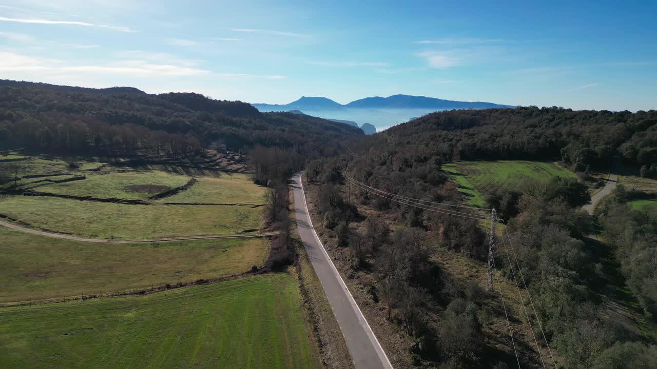 在湛蓝的天空下，风景优美的道路蜿蜒穿过郁郁葱葱的田野和树木繁茂的山丘视频素材